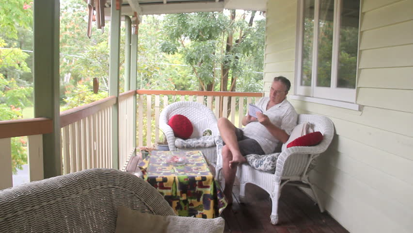 Mature man sitting and relaxing on his verandah playing sudoku.
