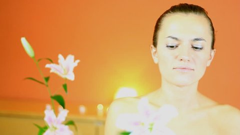 Young attractive woman gently touching the skin with a flower