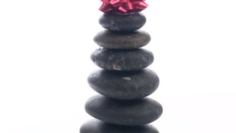 Zen or massage rocks and holiday bow against white background zoom-out