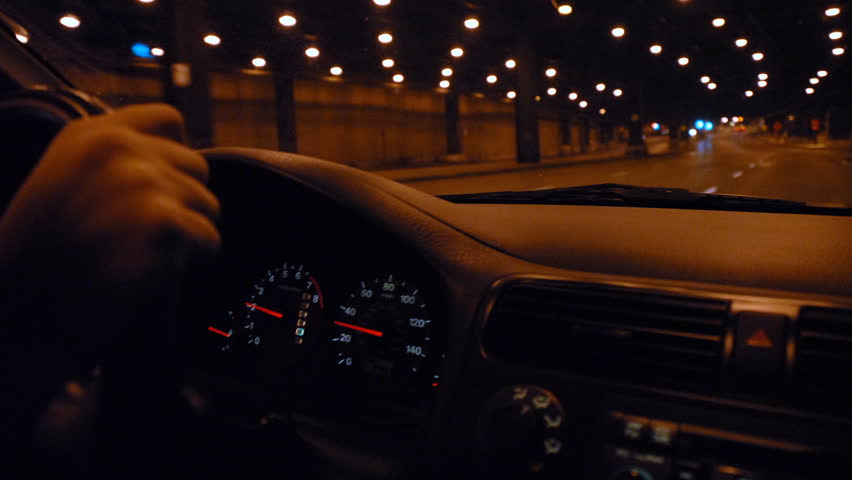 Hands on steering wheel driving through city tunnel at night time lapse