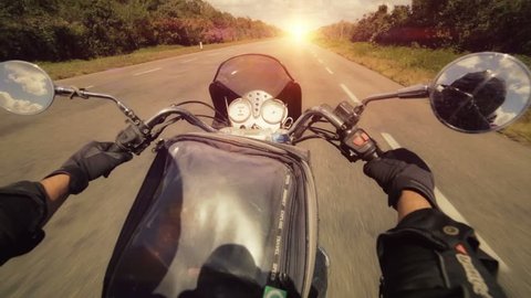 A motorcycle road adventure going forward to the sun in high speed. pov at sunset. 