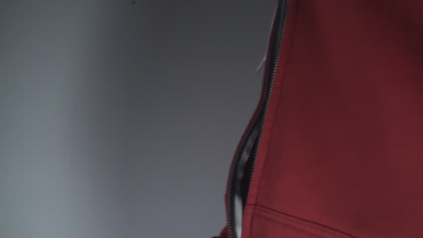Young Man Pulling Up A Zipper On A Red Shirt Side-Shot
