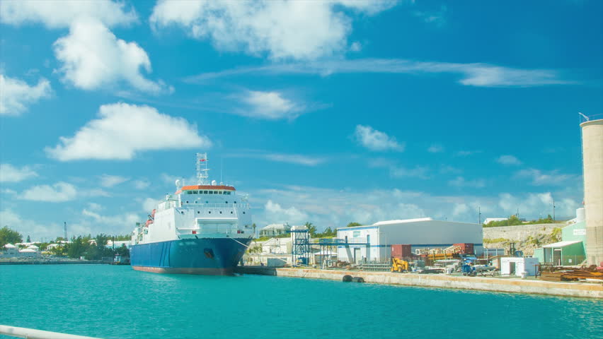 Cargo Ship in Tropical Water Docked at the Royal Naval Dockyard in Bermuda on a Sunny Day with White Clouds in a Blue Sky. All Recognizable Features Pertaining to the Vessel Hidden.