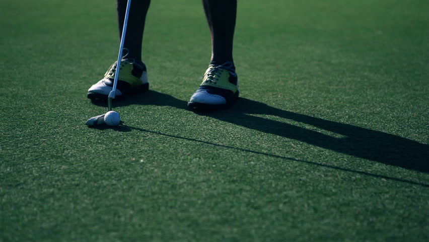 Golf player taking his putt on a beautiful green golf course