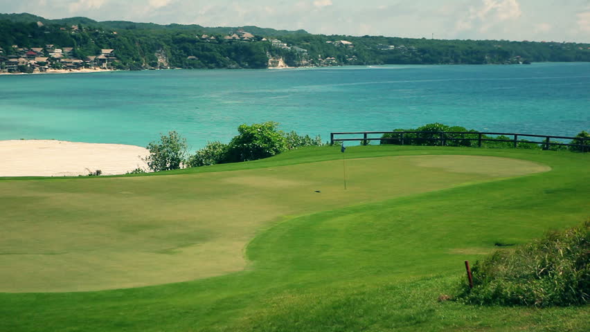 Amazing golf course with flag and ocean view in the background