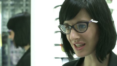 Female patient toys between two pairs of glasses and inspects herself in the mirror