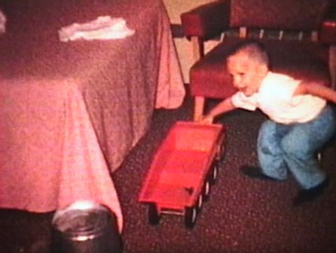 A cute little boy plays with his new toy truck and then rides on his tractor. (Vintage 8mm film)