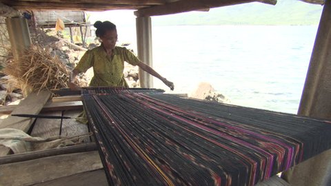 INDONESIA - CIRCA 2011 - Woman weaving in a hut circa 2011 in Indonesia.
