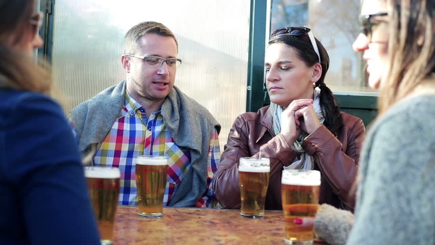 Friends talking and drinking beer in pub, steadycam shot.
