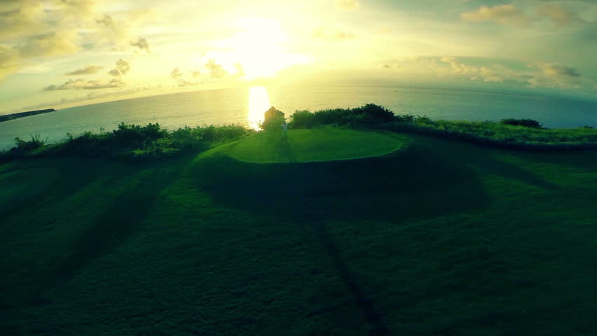 Aerial shot of a golfer teeing off on a beautiful golf course during sunset