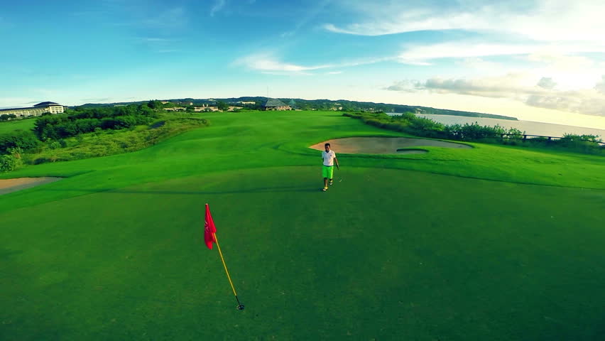 Aerial shot of a beautiful golf course with flag and golfer making his putt