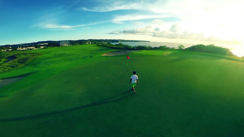 Aerial shot of a beautiful golf course with flag and golfer making his putt
