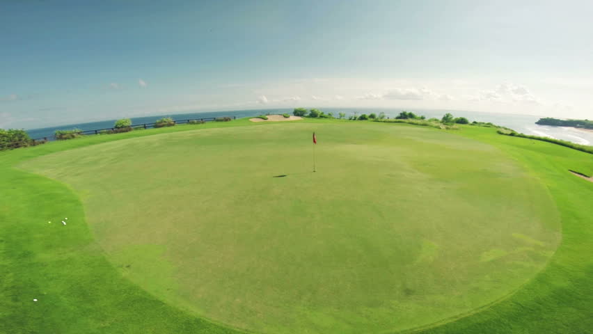 Aerial flight over amazing golf course with flag and ocean view in background