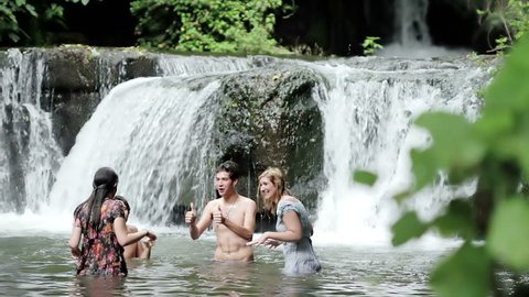 girls of boys have fun in a river - dancing, hugging and playing with water