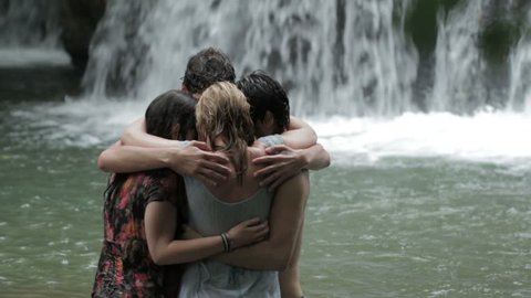 girls of boys have fun in a river. hugging and playing with water