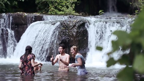 girls of boys have fun in a river - dancing, hugging and playing with water
