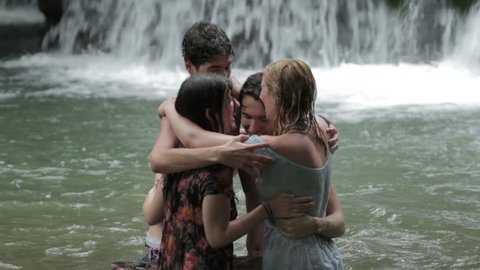 girls of boys have fun in a lake. hugging and playing with water