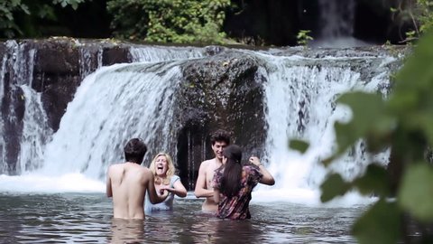 girls of boys have fun in a lake - dancing, hugging and playing with water
