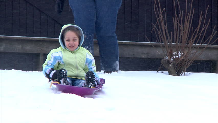 A little girl goes sled ridding.  Slow motion.