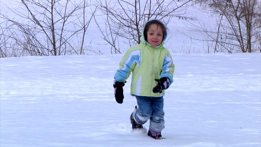A little girl runs towards the camera in the snow.  Slow motion.