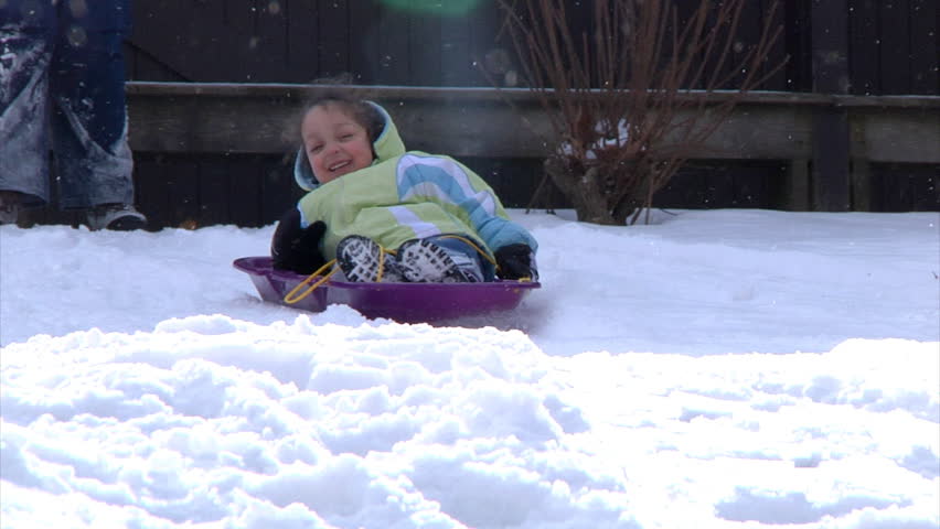 A little girl goes sled ridding.  Slow motion.