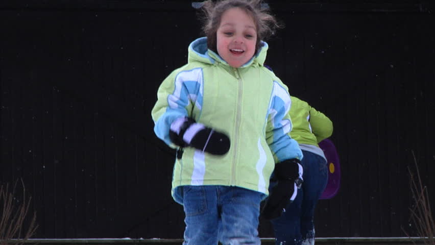 A little girl runs towards the camera in the snow.  Slow motion.
