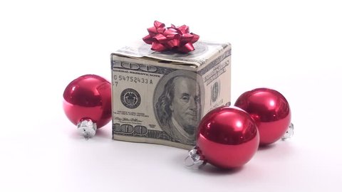 Seamless loop of gift box made of hundred dollar bills and holiday baubles isolated on white