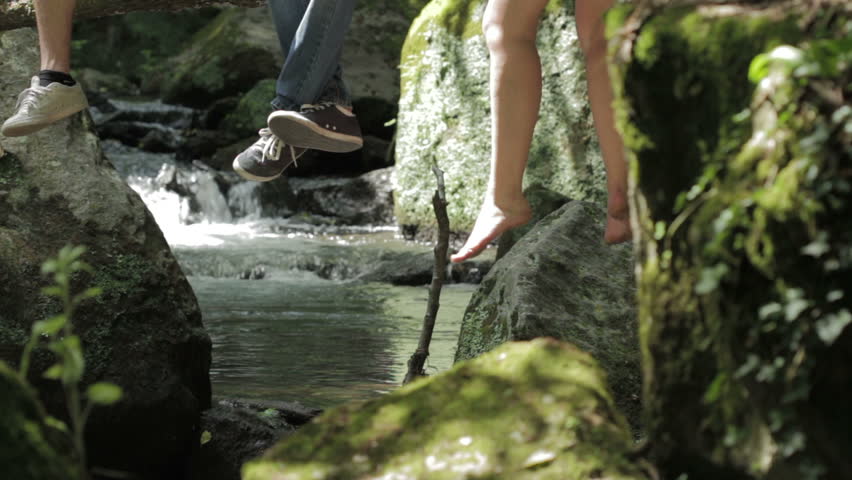 live in contact with the nature - legs dangling from a tree near a stream