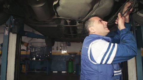 Auto mechanic repairing a car ( under a car lifts) - dolly