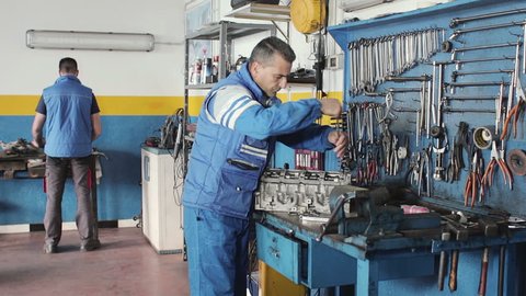 Auto mechanic repairing a car with socket wrench - dolly