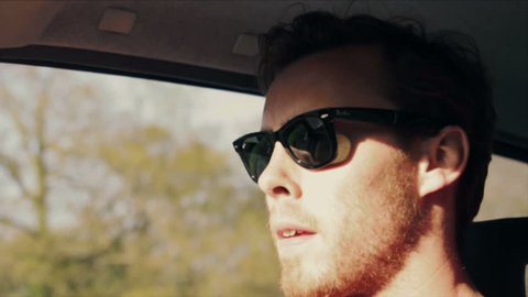 Young handsome male driving car in sunglasses, retro vintage colouring and lens flare