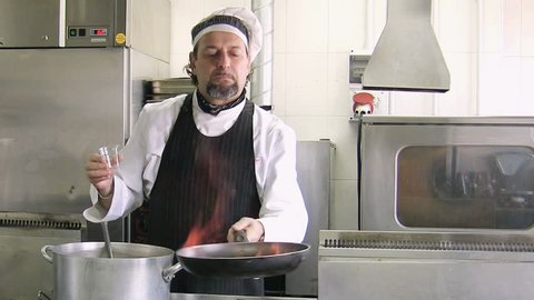 Man working as professional chef holding pan and cooking food in restaurant kitchen. Cook preparing lunch at work. Front view
