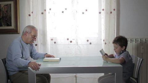the past and the future, grandfather reading a book and child uses tablet