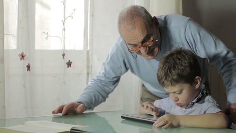 Grandfather and grandson using digital tablet together