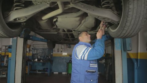 Auto mechanic repairing a car ( under a car lifts) - dolly