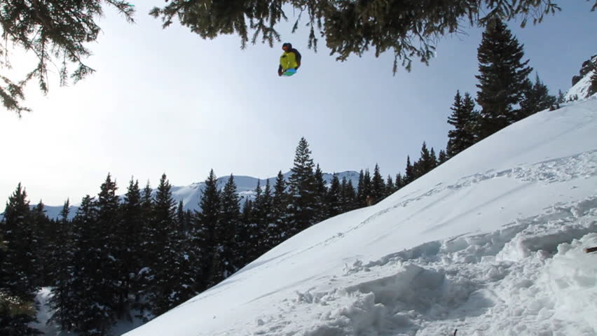 Snowboarders spinning off a backcountry jump in the mountains - 3 clips