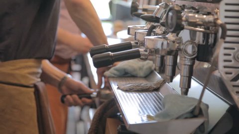 Professional barista prepares a latte in a busy coffee shop