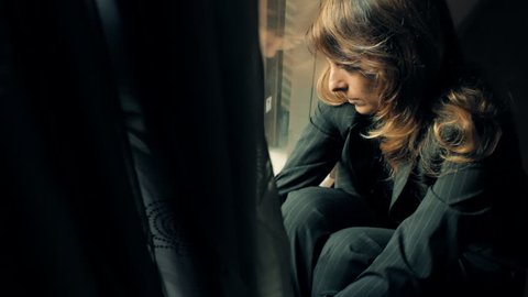 Sad businesswoman sitting on the floor near window