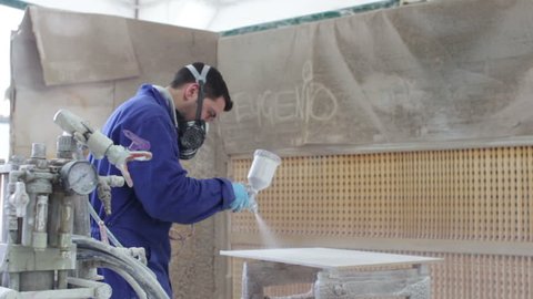 worker painting in a factory - industrial painting with spray gun - dolly