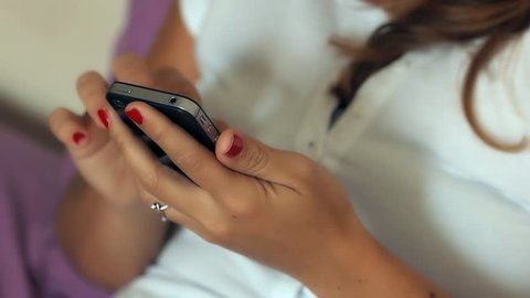 Brunette woman sending text message in bed in bedroom at home