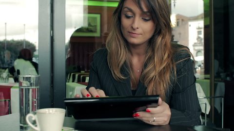 Businesswoman reading an article on her tablet computer. In a cafe.