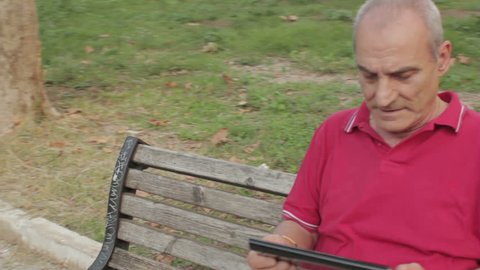 Senior man using tablet computer in park