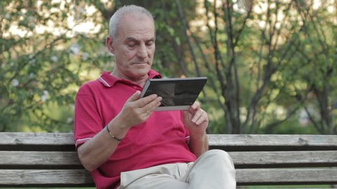 Senior man using tablet computer in park