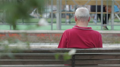 Sad senior man sits on the bench in park