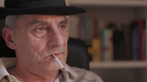Sad old man smokes a cigarette