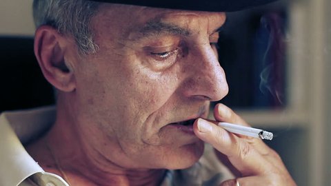 Close-up of a senior man thinking about something and smokes a cigarette