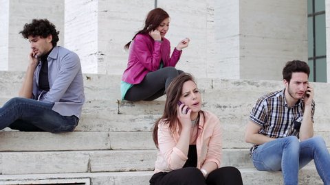 Four young people are on the phone sitting on a staircase - technology