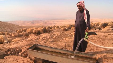 WADI RUM, JORDAN CIRCA 2013 - A Bedouin provides precious water for his flocks in the dry desert mountains of the Holy land.