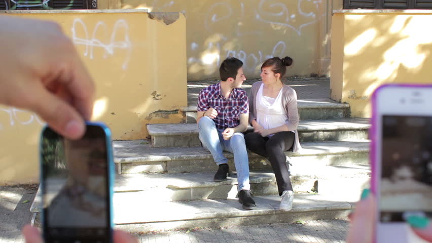 two lovers are taking pictures from friends - cell phone - kiss - photo