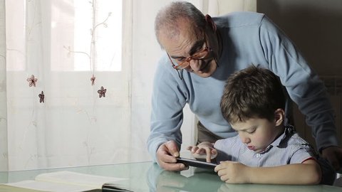 Child using tablet with his grandfather - touching tablet